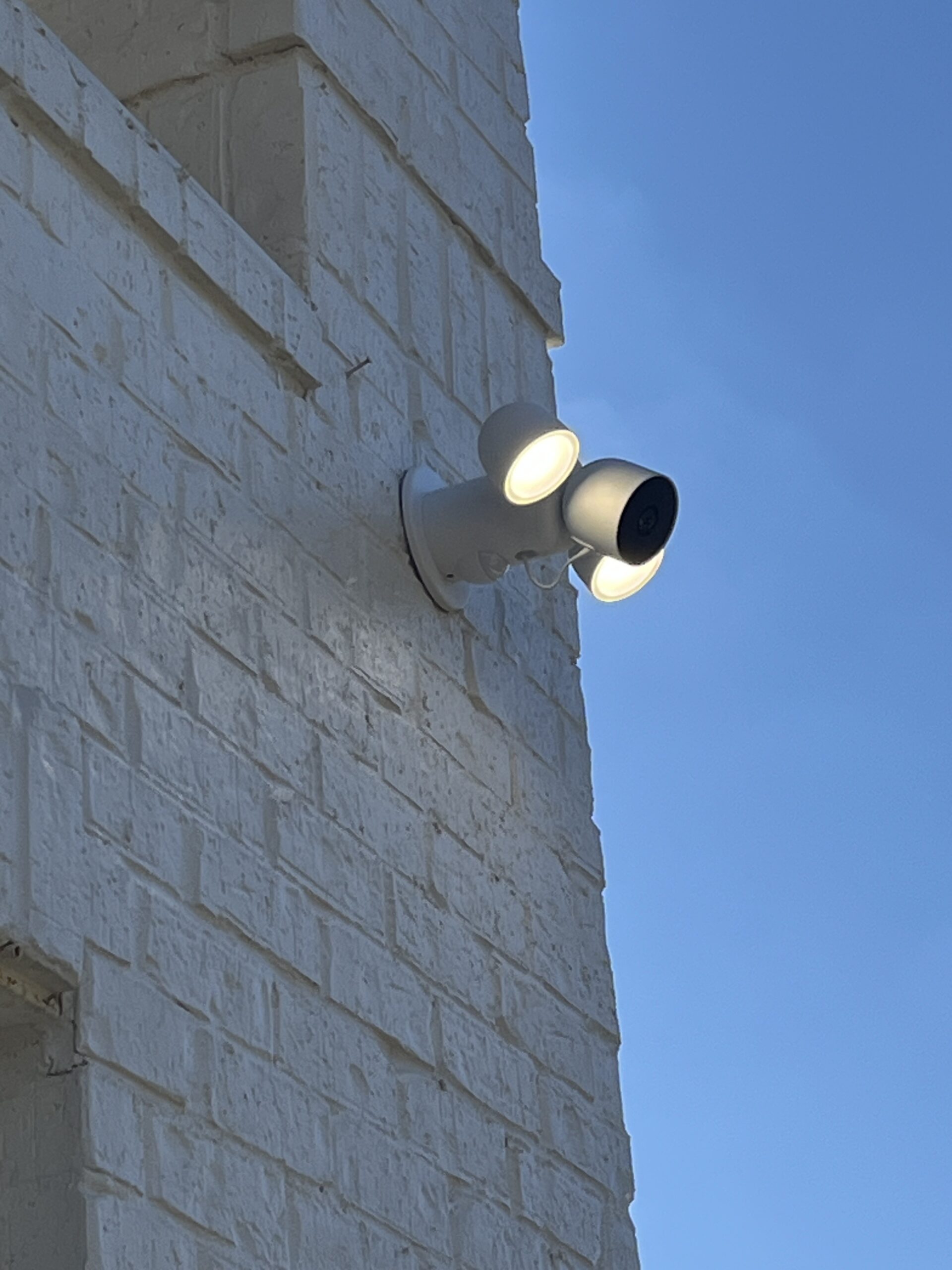 Floodlight camera installed on an exterior brick wall
